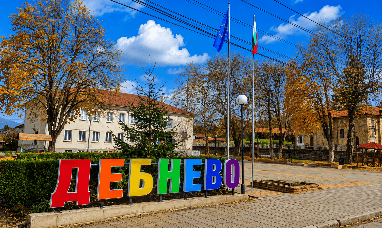 Цветната табела „Дебнево“ в центъра на селото, пред сградата на кметството и църквата
